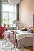 Bedroom with bed, fluffy carpet and plants on the windowsill