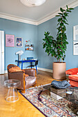 Living room with vintage armchair, light blue walls and large houseplant