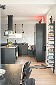 Kitchen with black cupboards and bookshelf