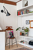 Living room corner with bookshelf, chair, patterned cushion and plants