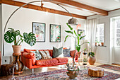 Living room with arc lamp, light red sofa and potted plants