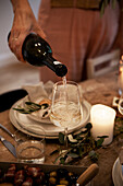 White wine is poured into a glass on a festively laid table by candlelight