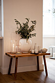 Wooden bench with twigs in white vase, lanterns and crockery