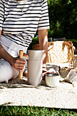 Picknick im Park mit Thermoskanne und Keramikbecher auf der Decke