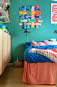 Colorful wall hanging above double bed in bedroom with blue walls