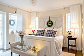 Bright bedroom with white upholstered bed and bouquets of flowers