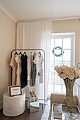 Elegant bedroom with clothes rack, shoes and roses in crystal vase