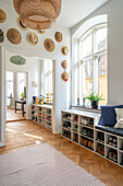 Hallway with shoe racks, seating and decorative hats on the wall