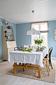 Walls painted light blue and dining table set with floral decorations