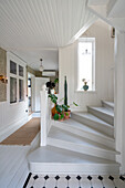 Hallway with white wood panelling and staircase, plants on steps