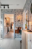 Hallway with patterned wallpaper and wooden elements, view into the kitchen