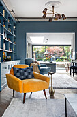 Yellow armchair in front of a blue wall of shelves in the living room