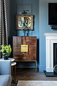 Elegant highboard in front of blue wall next to fireplace