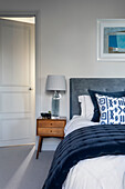 Doppelbett mit blauer Steppdecke aus Samt, daneben MId-Century Nachttisch im Schlafzimmer