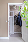 Hallway with patterned wallpaper and coat hooks on the wall