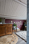 Children's room under a sloping roof with wooden furniture and bordeaux-coloured wall