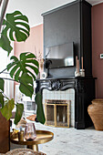 Living room with fireplace, monstera plant and golden side table