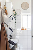 Bright bathroom with white tiles, hanging baskets and plant