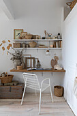 Wall shelf with decorative items and white metal chair