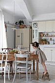 Girl at a rustic dining table in a bright country kitchen