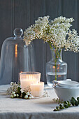 Stylish table decoration with flowers, candles, bowls, bell jars, and eucalyptus