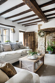 Living room with half-timbered ceiling, natural stone wall and rustic wooden door