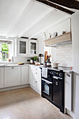 Country kitchen with white cupboards and modern black stove