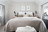 Schlafzimmer mit Doppelbett, Tagesdecke, Kissen und botanischen Wandbildern