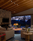 Sitting area with light leather furniture and natural stone wall at dusk