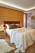 Bett mit weißer Bettwäsche und Wandpaneel im modernen Schlafzimmer