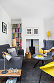 Modern eingerichtetes Wohnzimmer mit grauem Sofa und gelben Akzenten