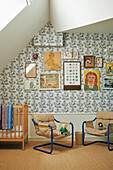 Children's room with patterned wallpaper and picture gallery on the sloping wall
