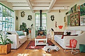 Helles Wohnzimmer mit Gemälden, Zimmerpflanzen und bunter Einrichtung