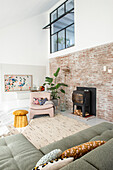 Bright, loft-style living room with brick wall, modern fireplace and seating furniture