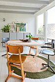 Bright dining room with round table, vintage chairs and natural-coloured carpet