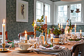 Festively laid dining table with candles and floral decorations in country house