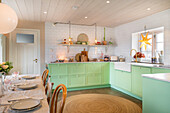 Hell eingerichtete Küche mit mintgrünen Schränken und weißer Metrofliesen-Rückwand