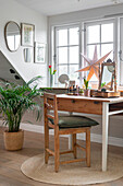 Holztisch und Holzstuhl, Zimmerpflanze und Dekostern am Fenster