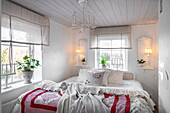 Brightly decorated bedroom with white wooden ceiling, chandelier and bed linen with red accents