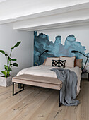 Modern eingerichtetes Schlafzimmer mit Wand in Aquarelloptik und Grünpflanze