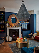 Gold-colored coffee table in front of fireplace in living room with blue walls and Christmas decorations