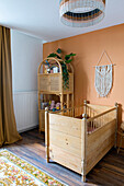 Kinderbett neben Bambusregal vor apricotfarbener Wand