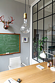 Antler decoration over chalkboard in study with window in the wall