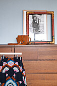 Colorful piece of clothing on chest of drawers with black and white photograph