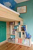 Helle Holzregale, darüber Stockbett im Kinderzimmer mit grünen Wänden