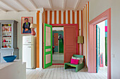 Blick in eine farbenfrohe Wohnung mit gestreiften Wandelementen und bunten Türen