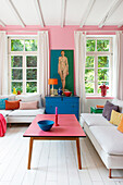 Helles Wohnzimmer mit farbenfroher Dekoration und Zentralperspektive