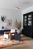 Modern living room with pink leather armchair and black display cabinet