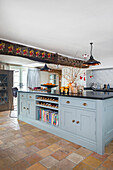 Country kitchen with blue base units, terracotta tiles and Christmas garland