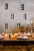 Dining table set with bales of straw and candlelight in front of a white stone wall